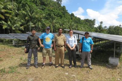 Tim Technical dan Community Engagement NZMATES berfoto bersama Camat Pulau Kur di depan instalasi panel surya desa  Lokwirin